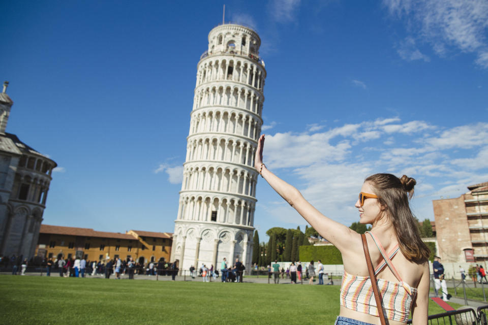 A tourist posing in front of the Leaning Tower of Pisa