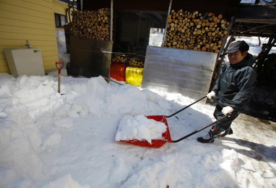 In this Monday, March 3, 2014 photo, Kunio Kikuchi, who is hearing impaired, shovels snow at Huck's House, a vocational center for the disabled in Tanohata, northeastern Japan. Kikuchi does chores at the center which opened to tsunami survivors who lost their homes when the March 11, 2011 tsunami hit the town. (AP Photo/Junji Kurokawa)