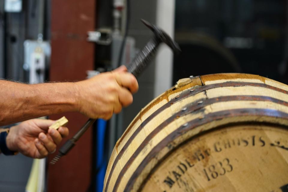 A member of the staff opens an oak barrel for the first process of filtration before bottling, Tuesday, Oct. 3, 2023, at Boone County Distilling Company.