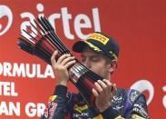 Red Bull Formula One driver Sebastian Vettel of Germany kisses his trophy on the podium after winning the Indian F1 Grand Prix at the Buddh International Circuit in Greater Noida, on the outskirts of New Delhi, October 27, 2013. REUTERS/Ahmad Masood