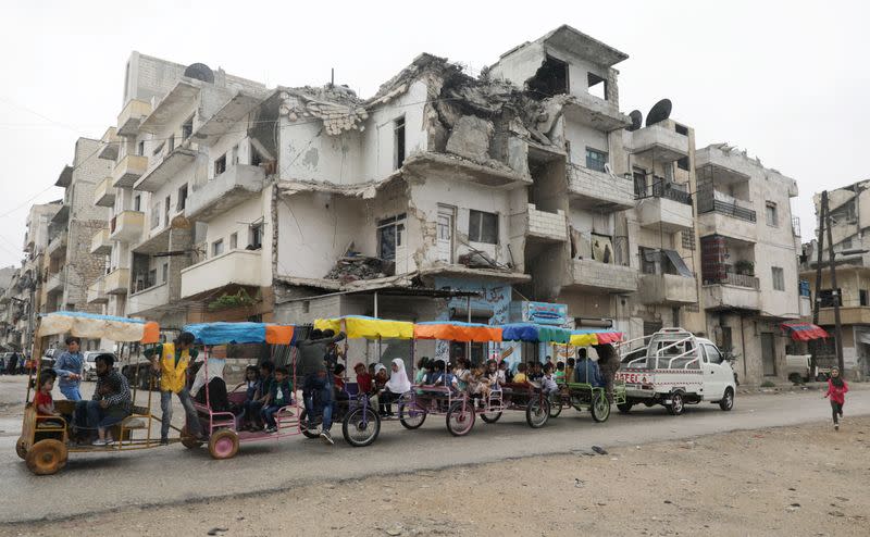 Children ride in carts on the first day of the Muslim holiday of Eid al-Fitr in Idlib city