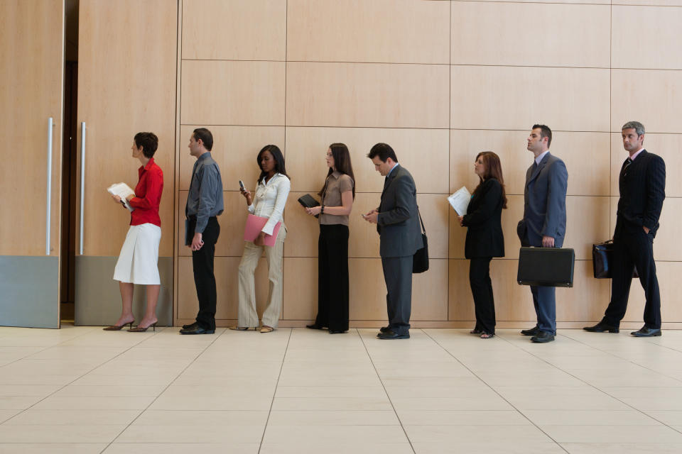 A line of office workers waiting near big doors