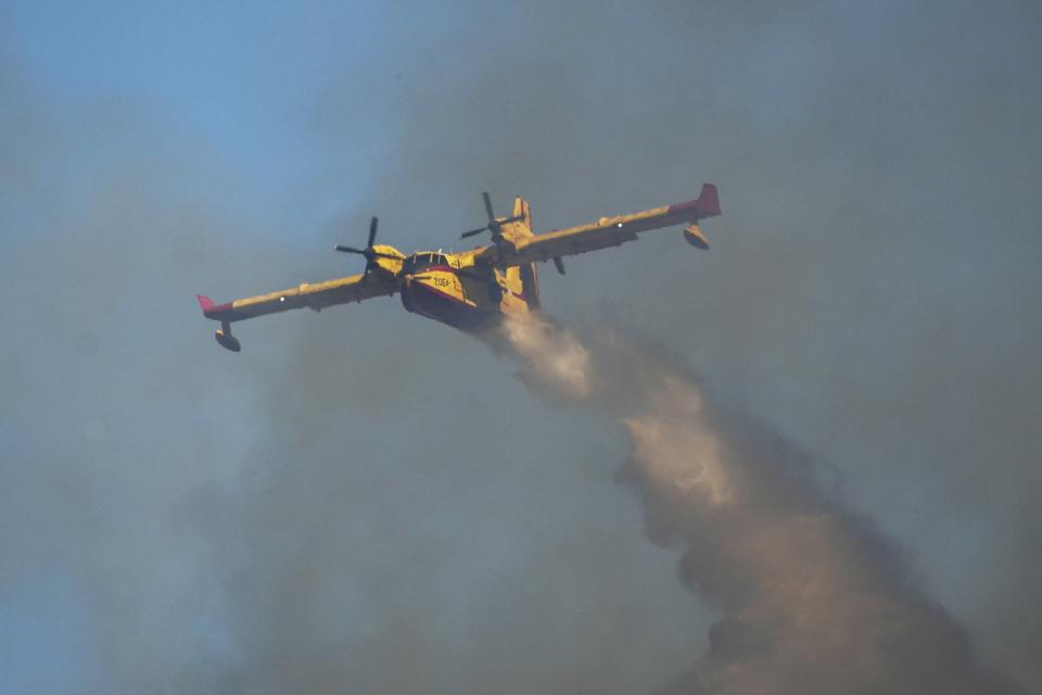 A Canadair aircraft drops water over a wildfire in Vati village, on the Aegean Sea island of Rhodes, southeastern Greece, on Tuesday, July 25, 2023. A third successive heat wave in Greece pushed temperatures back above 40 degrees Celsius (104 degrees Fahrenheit) across parts of the country Tuesday following more nighttime evacuations from fires that have raged out of control for days. (AP Photo/Petros Giannakouris)