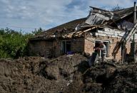 Un hombre lanza los escombros de una casa residencial en el cráter dejado por un ataque de misiles rusos en el asentamiento de Kushuhum