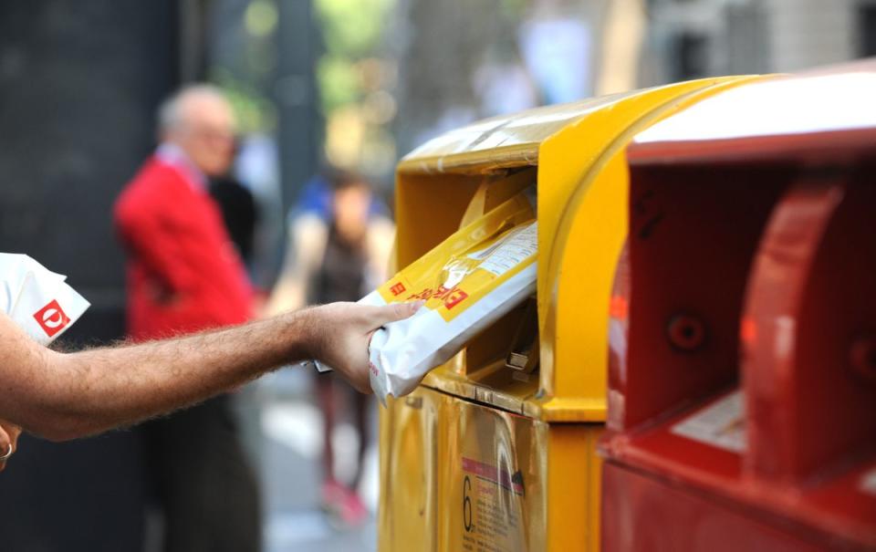 A man posting mail at an Australia Post postbox in Sydney.