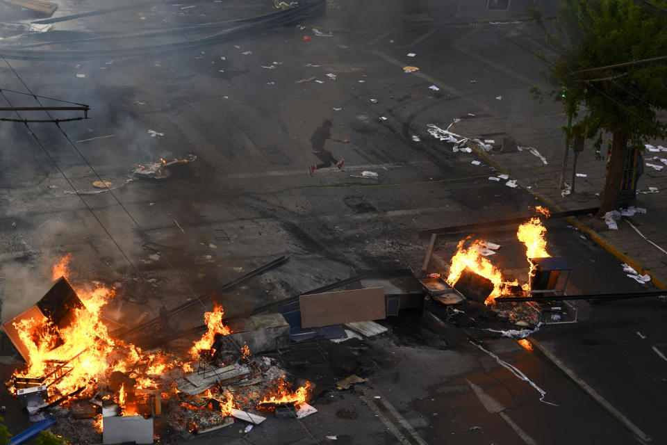 An anti-government protester runs near a burning barricade in Valparaiso, Chile, Friday, Oct. 25, 2019. A new round of clashes broke out Friday as demonstrators returned to the streets, dissatisfied with economic concessions announced by the government in a bid to curb a week of deadly violence.(AP Photo/Matias Delacroix)