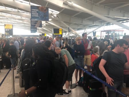 Passengers wait in long queues at Heathrow Airport as IT problems caused flight delays in London