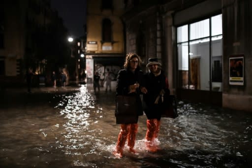 Tourists waded in thigh-high galoshes or barefoot through the submerged alleys