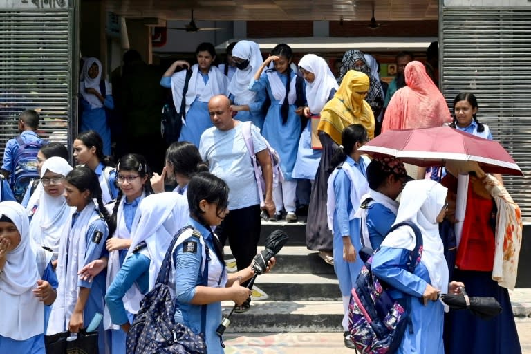 Unas estudiantes salen de una escuela, algunas con paraguas para protegerse del sol, el 28 de abril de 2024 en Daca, la capital bangladesí (Munir Uz Zaman)