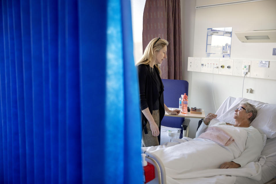 Dr. Jennifer Stevens, a pain specialist, talks with patient Cheryl Rowley who is awaiting surgery at St. Vincent's Hospital in Sydney, Australia, Wednesday, July 17, 2019. "We were just pumping this stuff out into our local community, thinking that that had no consequences," says Stevens, a vocal advocate for changing opioid prescribing practices. "And now, of course, we realize that it does have huge consequences." (AP Photo/David Goldman)