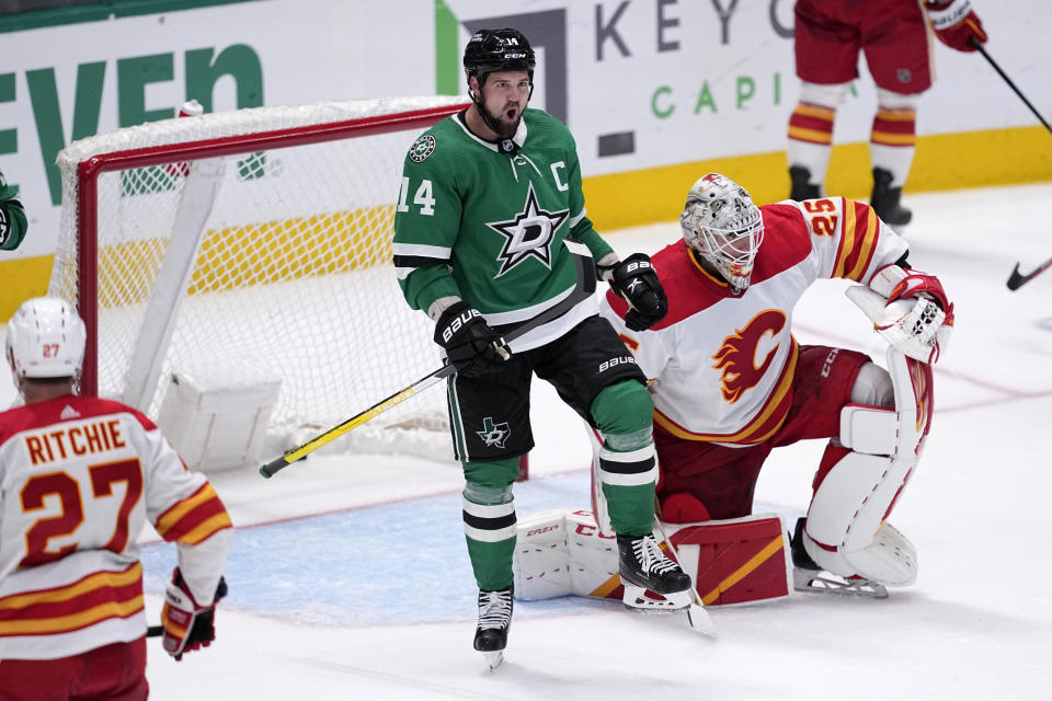 Dallas Stars left wing Jamie Benn (14) celebrates after scoring against Calgary Flames' Jacob Markstrom (25) as Flames' Nick Ritchie (27) looks on in the third period of an NHL hockey game, Monday, March 6, 2023, in Dallas. (AP Photo/Tony Gutierrez)