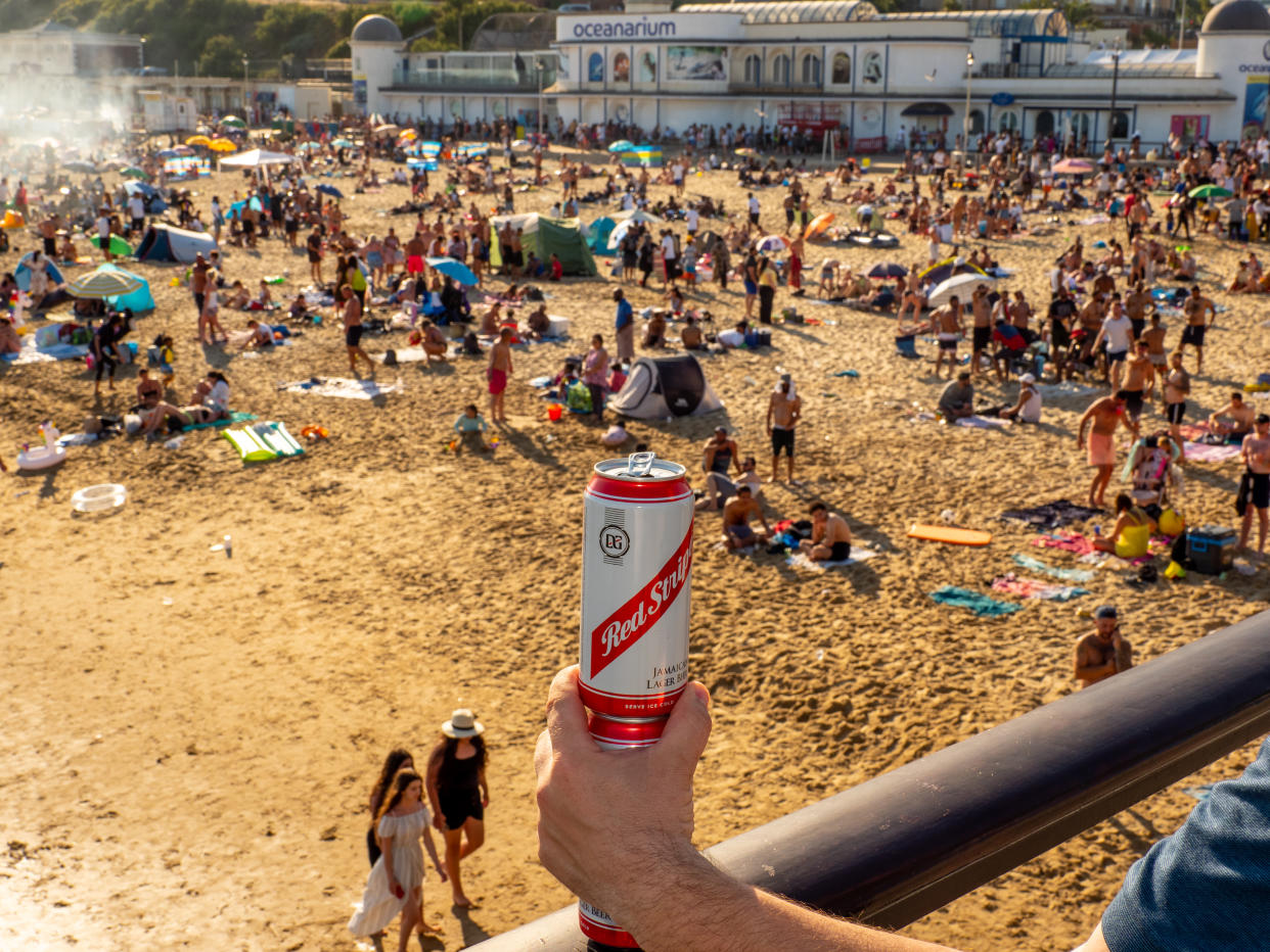 BOURNEMOUTH, UNITED KINGDOM - JUNE 25:  A can of lager is held as a crowd forms on Bournemouth beach on June 25,2020 in Bournemouth,England. A major incident was declared after thousands of people defied advice to stay away and descended on Bournemouth beach on the hottest day of the year so far. Services were overstretched as visitors arrived in large volumes, with Bournemouth, Christchurch and Poole Council issuing a record 558 parking enforcement fines. (Photo by Peter Dench/Getty Images)