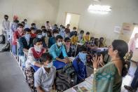 Students wearing facemasks or scarves to protect the face attend a class at a governement-run high school in Secunderabad.