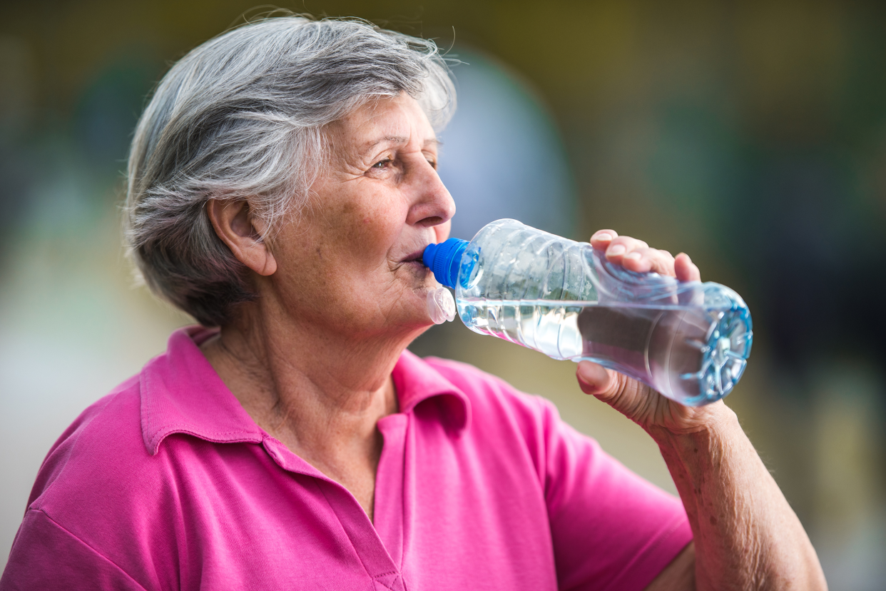 Older woman drinking from a plastic water bottle
