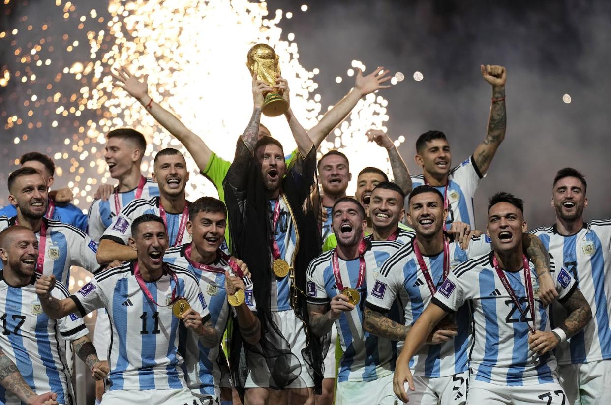 Argentina's football players celebrate with the World Cup trophy after winning the final match with France at the Lusail Stadium in Lusail, Qatar. (AP Photo/Martin Meissner)