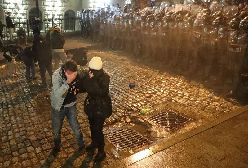 Manifestantes se cubren la cara por el gas lacrimógeno utilizado por la policía durante una concentración contra la ley de "agentes extranjeros" en Tiflis