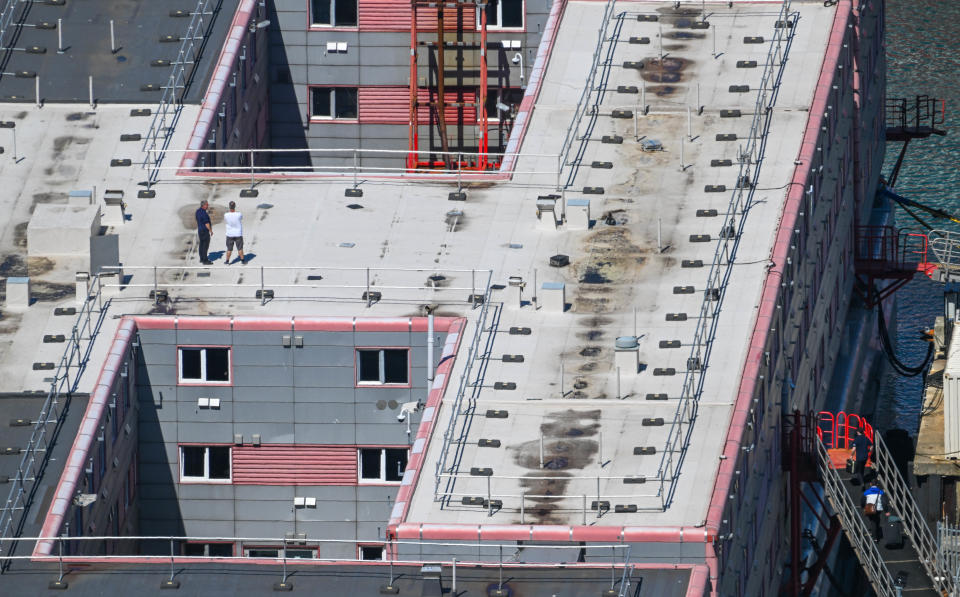 PORTLAND, ENGLAND - AUGUST 09: People walk on the roof of the Bibby Stockholm immigration barge as people board with suitcases, in Portland Port, on August 09, 2023 in Portland, England. The first residents arrived on August 7th as the British government seeks to relocate asylum seekers from government-leased hotels. The Home Office says the vessel can accommodate up to 500 migrants and rejected criticism that the facility is unsafe. (Photo by Finnbarr Webster/Getty Images)