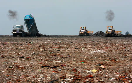 FILE PHOTO: Staff operate heavy machinery at the Semakau Landfill in Singapore April 25, 2007. The island located south of Singapore is the country's only landfill for waste disposal. REUTERS/Nicky Loh/File Photo