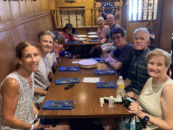 kari's family sitting at a long table at liberty tree tavern in disney worl d