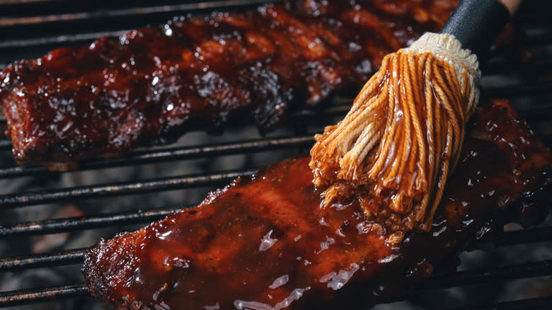 ribs on a grill being sauced