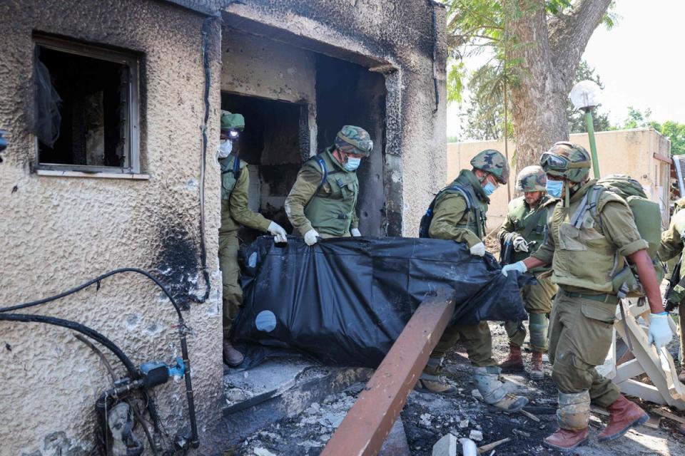 Israeli soldiers remove the body of an Israeli, killed during an attack by Palestinian militants, in Kfar Aza, Israel (AFP via Getty Images)