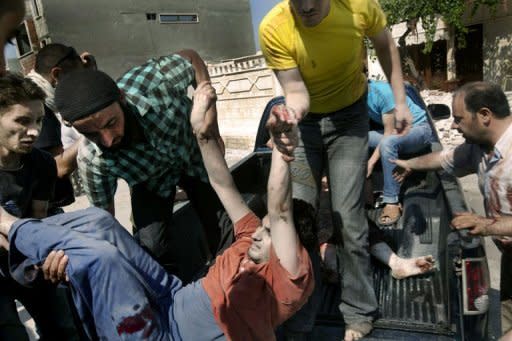 A wounded Syrian man is lifted off the back of a pick-up truck following shelling by Syrian government forces on al-Qusayr, close to the restive city of Homs