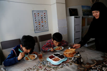Gulgine Mahmut places food on the table as her sons Mohammed, 10, and Hamza, 9, eat lunch at their home in Istanbul, Turkey, February 28, 2019. REUTERS/Murad Sezer