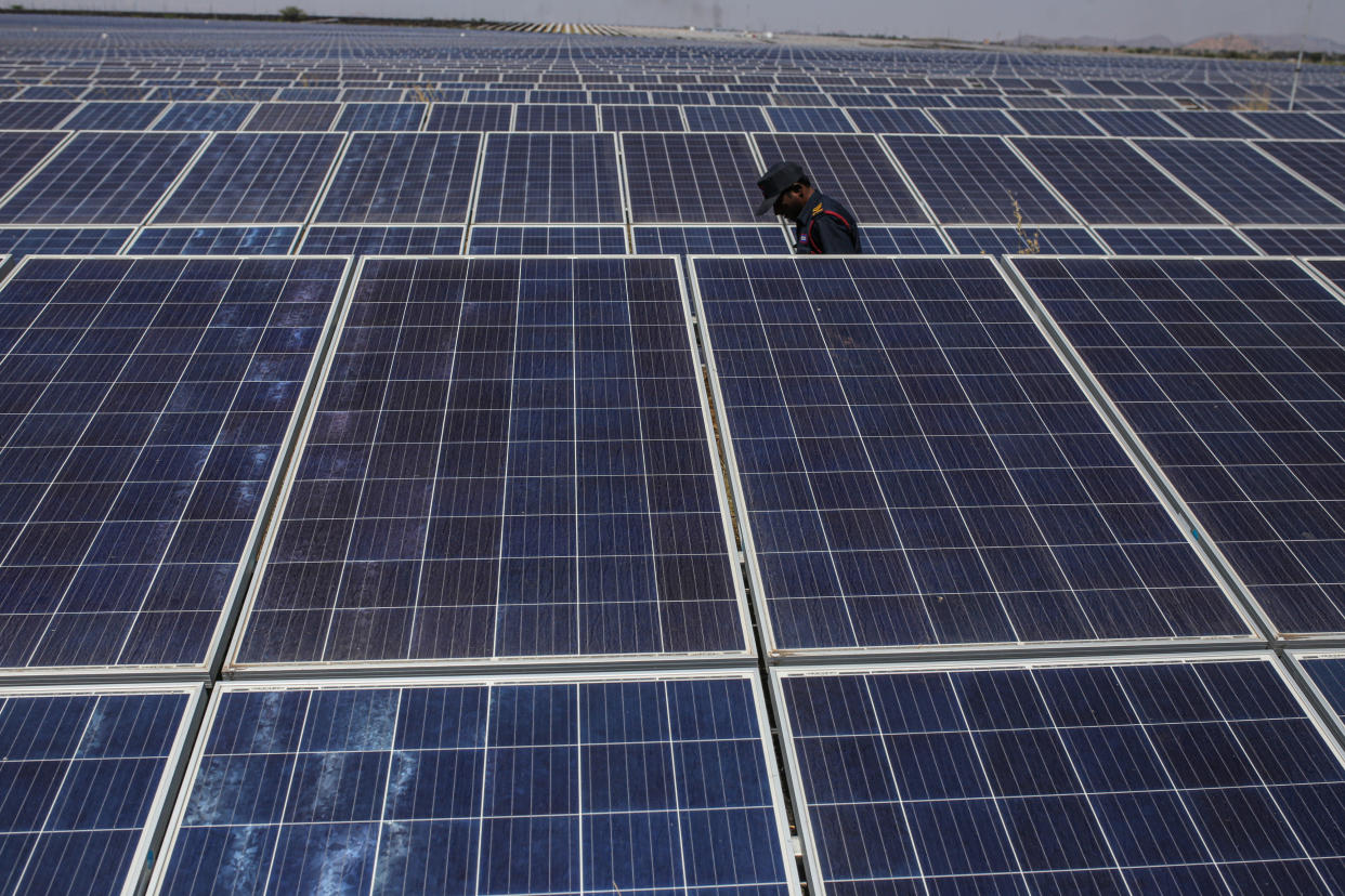 A guard walks between photovoltaic panels at a solar farm in Pavagada, Karnataka, India, February 24, 2022. / Credit: Dhiraj Singh/Bloomberg via Getty