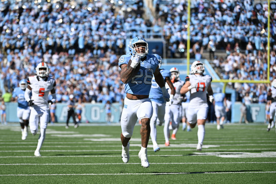 Nov 4, 2023; Chapel Hill, North Carolina, USA; North Carolina Tar Heels running back Omarion Hampton (28) runs as Campbell Fighting Camels linebackers Lakeem Rudolph (5) and Taylor Behl (17) defend in the first quarter at Kenan Memorial Stadium. Mandatory Credit: Bob Donnan-USA TODAY Sports