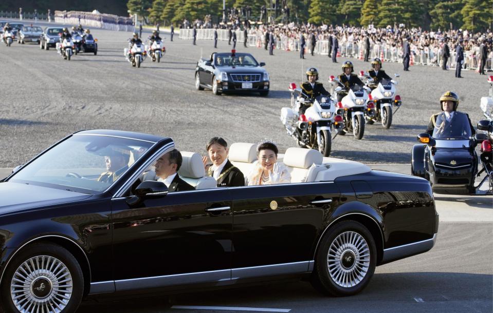 Japanese Emperor Naruhito, center left, and Empress Masako, center right, wave to spectators during the royal motorcade in Tokyo, Sunday, Nov. 10, 2019.(Shigeyuki Inakumao/Kyodo News via AP)