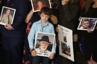 Aiden Hall holds a photo of his grandfather Tom Hall, a victim of a distracted driver, as he stands with other family members who lost loved ones linked to distracted driving, at a bill signing ceremony for a law against distracted driving at the Arizona Capitol Monday, April 22, 2019, in Phoenix. Arizona becomes the 48th state to ban texting and the 18th to ban any hand-held phone use while driving. Officers can begin issuing warnings immediately and can write tickets in 2021. (AP Photo/Ross D. Franklin)