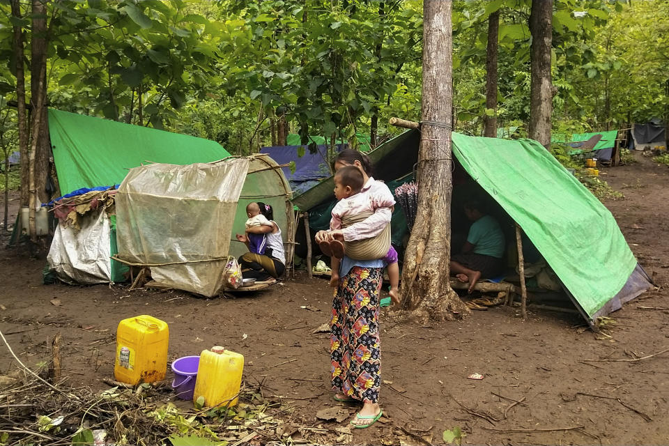 An internally displaced woman carries a child outside makeshift tents at Pu Phar Village, Demawso Township, Kayah State on Thursday June 17, 2021. A report on the situation in conflict-affected areas of Myanmar issued this week by the U.N.'s Office for the Coordination of Humanitarian Affairs says around 108,800 people from Kayah State were internally displaced following an escalation of hostilities between the government military and the local Karenni People's Defense Force militia since the coup Feb. 1, 2021. (AP Photo)