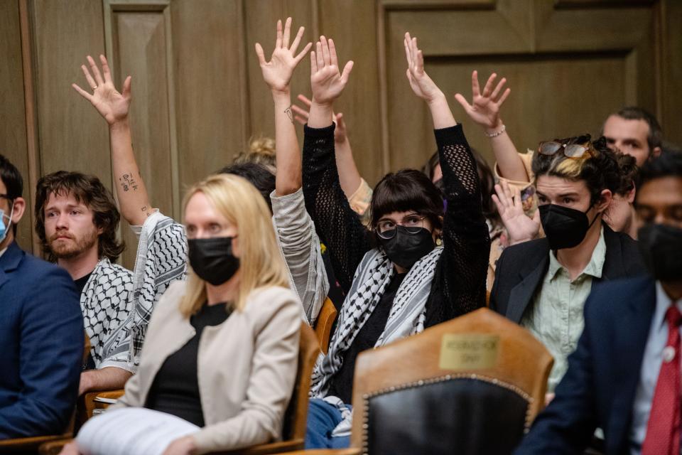 Supporters of a cease fire resolution raise their hands in the air to silently clap during public comment at the Asheville City Council meeting, March 12, 2024.