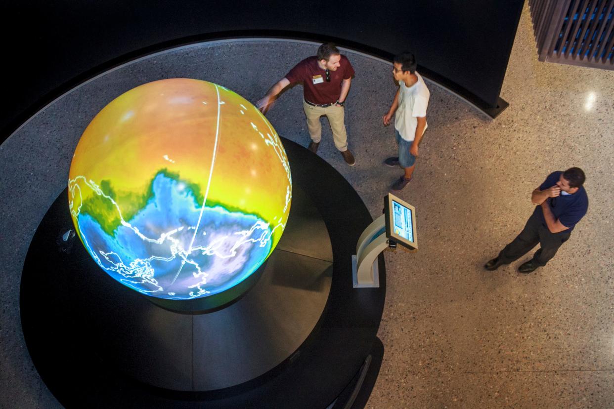 Visitors look at the Magic Planet, a digital video globe inside the new Interdisciplinary Science and Technology Building 4 on Arizona State University's Tempe campus, on the day of its dedication, Wednesday, Sept. 19, 2012. The $185 million building is the largest single research building at ASU, and the most expensive one to date, and houses some of the university's signature programs including the School of Earth & Science Exploration.