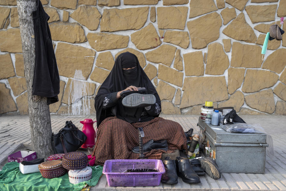 An Afghan woman cleans customers's shoes in a street in Kabul, Afghanistan, Sunday, March 5, 2023. After the Taliban came to power in Afghanistan, women have been deprived of many of their basic rights. (AP Photo/Ebrahim Noroozi)