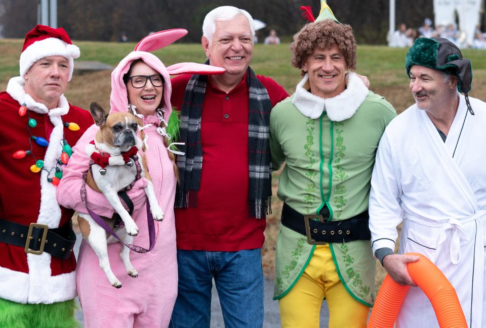 Phil Williams, lead investigative reporter at NewsChannel 5, takes a moment to be photographed with some famous Christmas movie characters, from left, the Grinch, Ralphie, Buddy the Elf and Cousin Eddie, before the Franklin Christmas Parade in Franklin, Tenn., Saturday, Dec. 2, 2023.