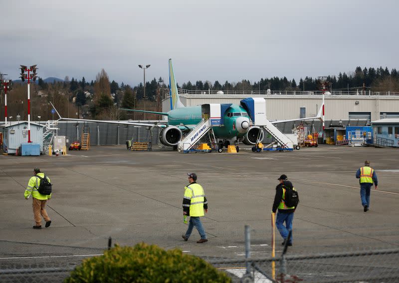 Employees walk past a Boeing 737 Max aircraft at Boeing's 737 Max production facility in Renton