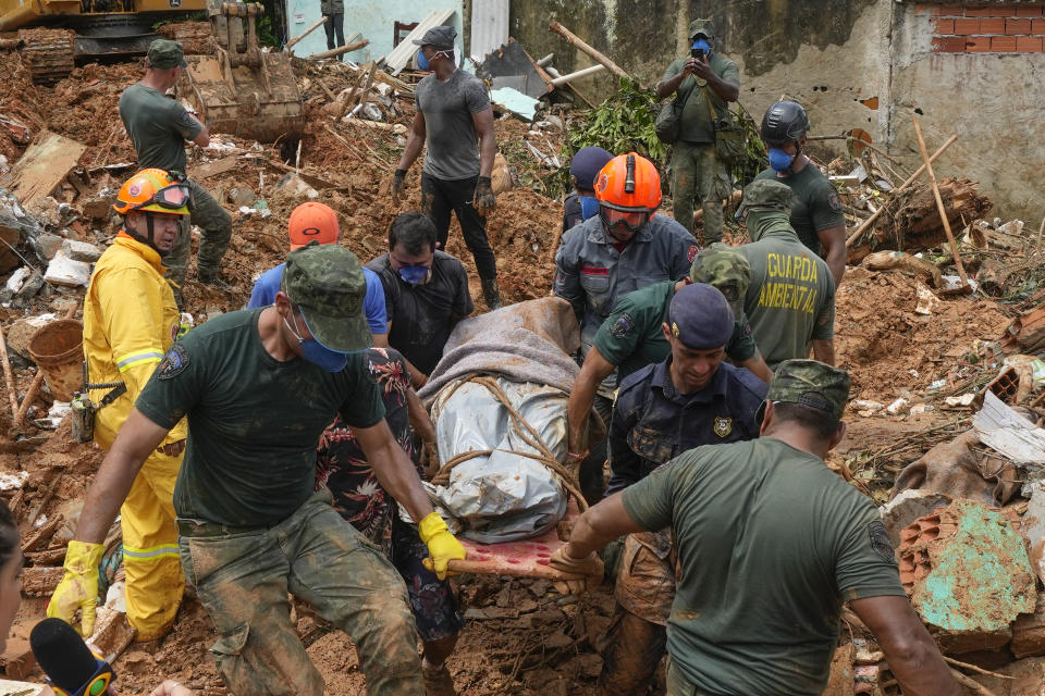 Rescue workers and volunteers carry the body of a landslide victim near Barra do Sahi beach after heavy rains in the coastal city of Sao Sebastiao, Brazil, Wednesday, Feb. 22, 2023. (AP Photo/Andre Penner)