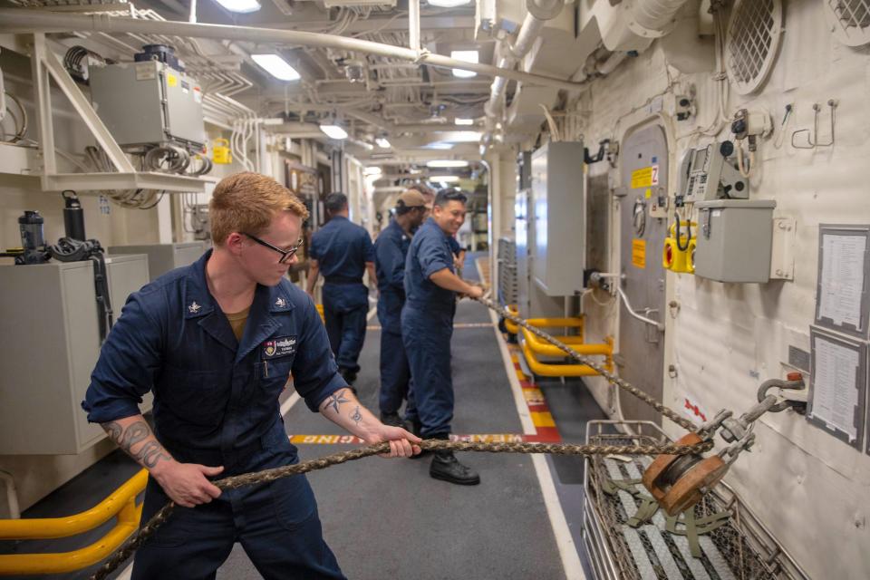 Sailors handle line aboard USS Zumwalt