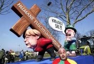 A carnival float with papier-mache caricatures mocking Bavarian Governor Horst Seehofer and German Chancellor Angela Merkel is displayed at a postponed "Rosenmontag" (Rose Monday) parade, at one location in Duesseldorf, Germany, March 13, 2016, after the original parade in February was cancelled due to severe weather. Words read 'crucify her' 'human politics for migrants'. REUTERS/Ina Fassbender