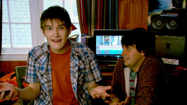 Bo with his arms outstretched as he sits next to a friend in a scene from the show