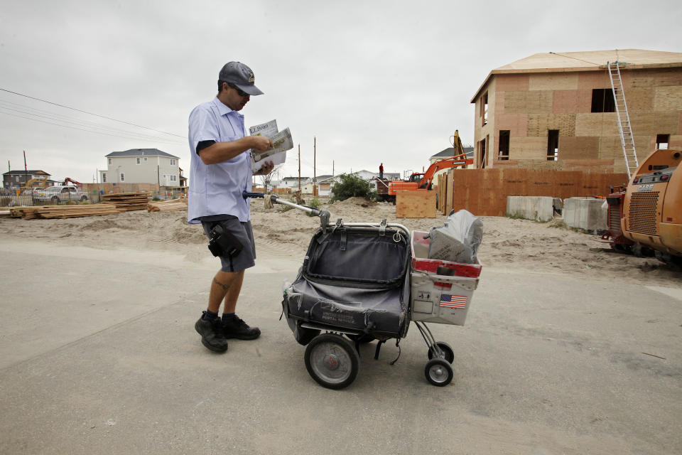 FILE - In this Oct. 17, 2013 file photo, a postal carrier makes his rounds through Breezy Point, in the Queens borough of New York. The house on the right will replace one of the homes that burned to the ground during Superstorm Sandy in October 2013. Criticizing New York City’s “Build it Back” program as “overly complex,” New York City Mayor Bill de Blasio announced on Thursday, April 17, 2014, reforms to the program meant to aid New Yorkers repairing damage left in the wake of Superstorm Sandy. (AP Photo/Mark Lennihan, File)