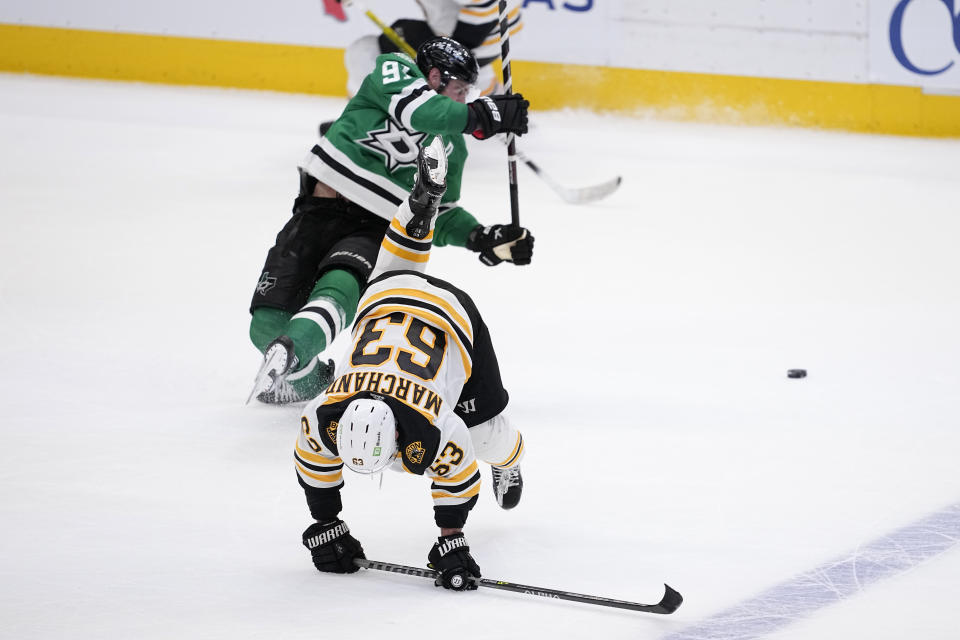 Boston Bruins left wing Brad Marchand (63) and Dallas Stars' Tyler Seguin (91) fall to the ice after colliding in overtime of an NHL hockey game, Tuesday, Feb. 14, 2023, in Dallas. Marchand was issued a penalty on the play for interference. (AP Photo/Tony Gutierrez)