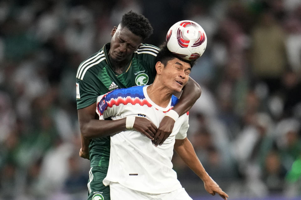 Saudi Arabia's Awn Alsalluli, background, and Thailand's Teerasak Poeiphimai jump for the ball during the Asian Cup Group F soccer match between Saudi Arabia and Thailand at Education City Stadium, in Al Rayyan, Qatar, Thursday, Jan. 25, 2024. (AP Photo/Aijaz Rahi)