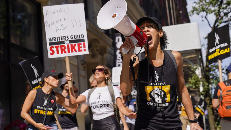 A strike captain, right, leads the chants as strikers walk a picket line outside Warner Bros., Discovery and Netflix offices in Manhattan on Friday, Aug. 18, 2023.