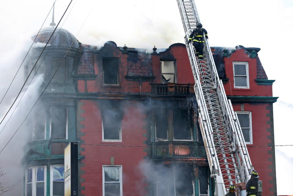 In this file photo, a New Bedford firefighter is seen ascending a ladder up to the top of the Royal Crown Lodge in New Bedford during the March 28 fire.