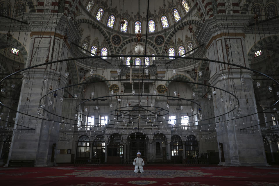 Esat Sahin, imán de la emblemática mezquita Fatih de Estambul, preside las oraciones en un recinto desierto debido a la cuarentena del coronavirus, 24 de abril de 2020, primer día del mes santo musulmán del Ramadán. (AP Foto/Emrah Gurel)