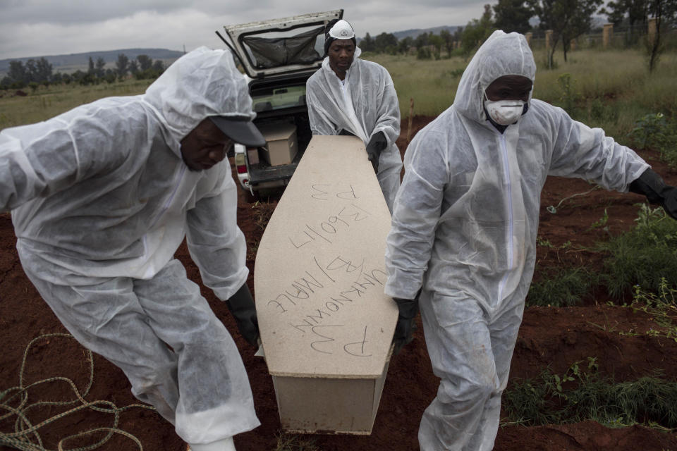 In this Thursday, April 12, 2018 photo, mortuary workers carry the coffin of an unidentified man for burial at a cemetery outside Johannesburg. At least five bodies of unidentified people are buried on top of each other in each grave. (AP Photo/Bram Janssen)
