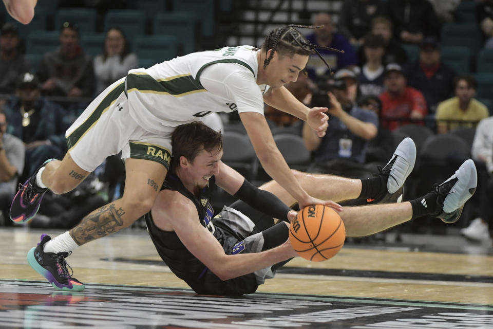 Colorado State guard Kyan Evans (0) and Washington forward Moses Wood (13) dive for a loose ball during the first half of an NCAA college basketball game Saturday, Dec. 2, 2023, in Las Vegas. (AP Photo/Sam Morris)