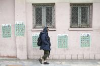 A woman walks past parliamentary election campaign posters in Tehran